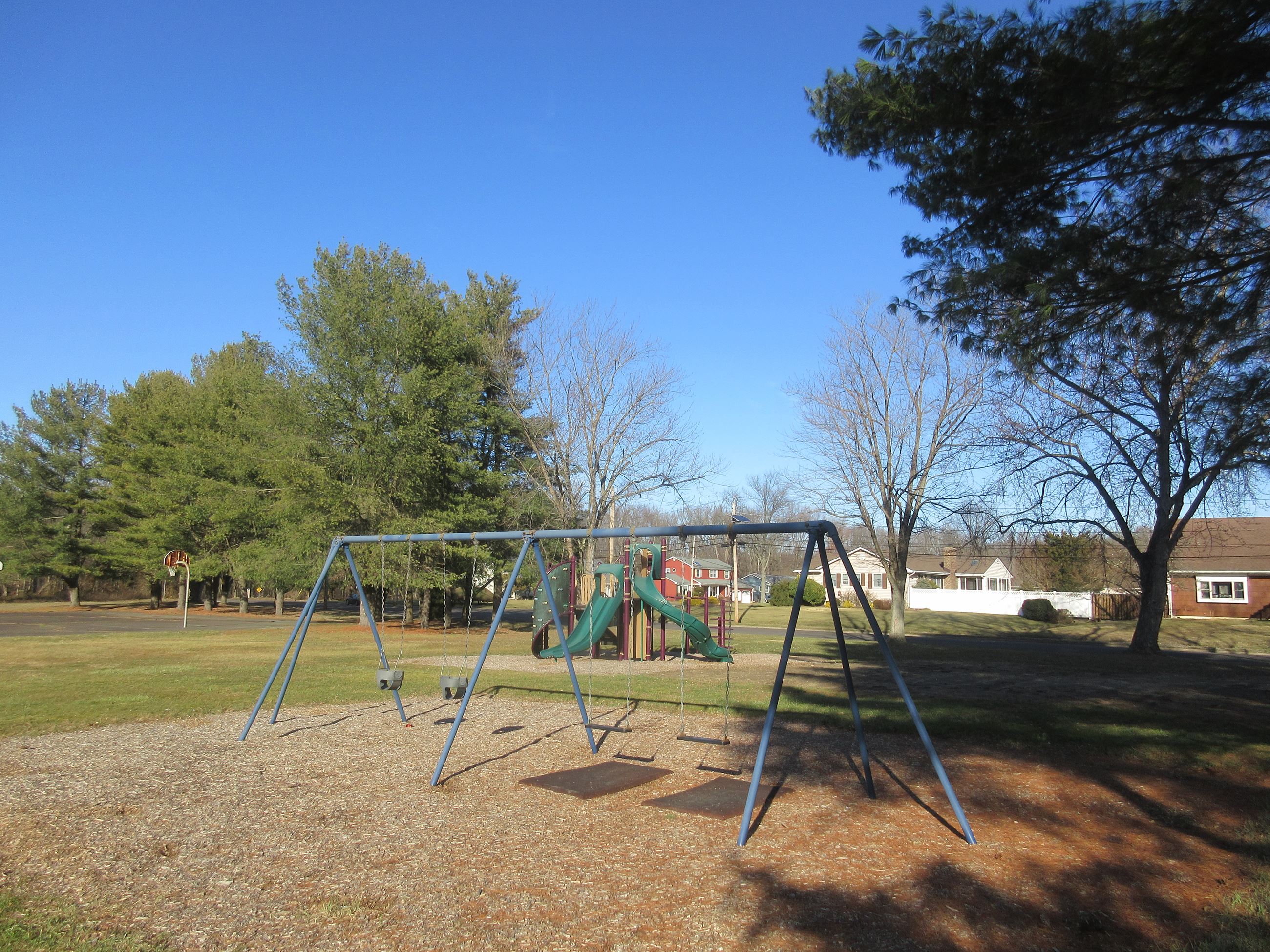 View of the swing set, activity center, and basketball court at Drialo Playground.