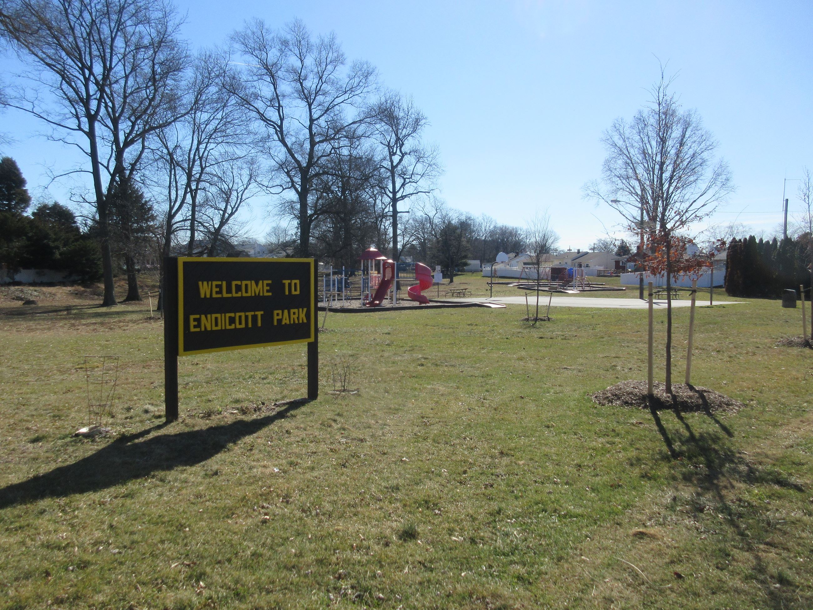 View of the park from Kendall Road showing the sign, activity centers, and basketball court.